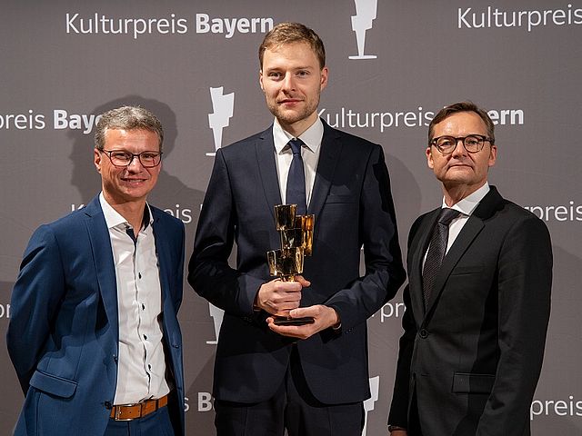 Martin Krechlak (Mitte) erhält den Kulturpreis Bayern 2019 als bester Absolvent der Hochschule für Musik Nürnberg. Überreicht wurde der Preis von Reimund Gotzel, Vorstandsvorsitzender der Bayernwerk AG (rechts), und Staatsminister Bernd Sibler (links)