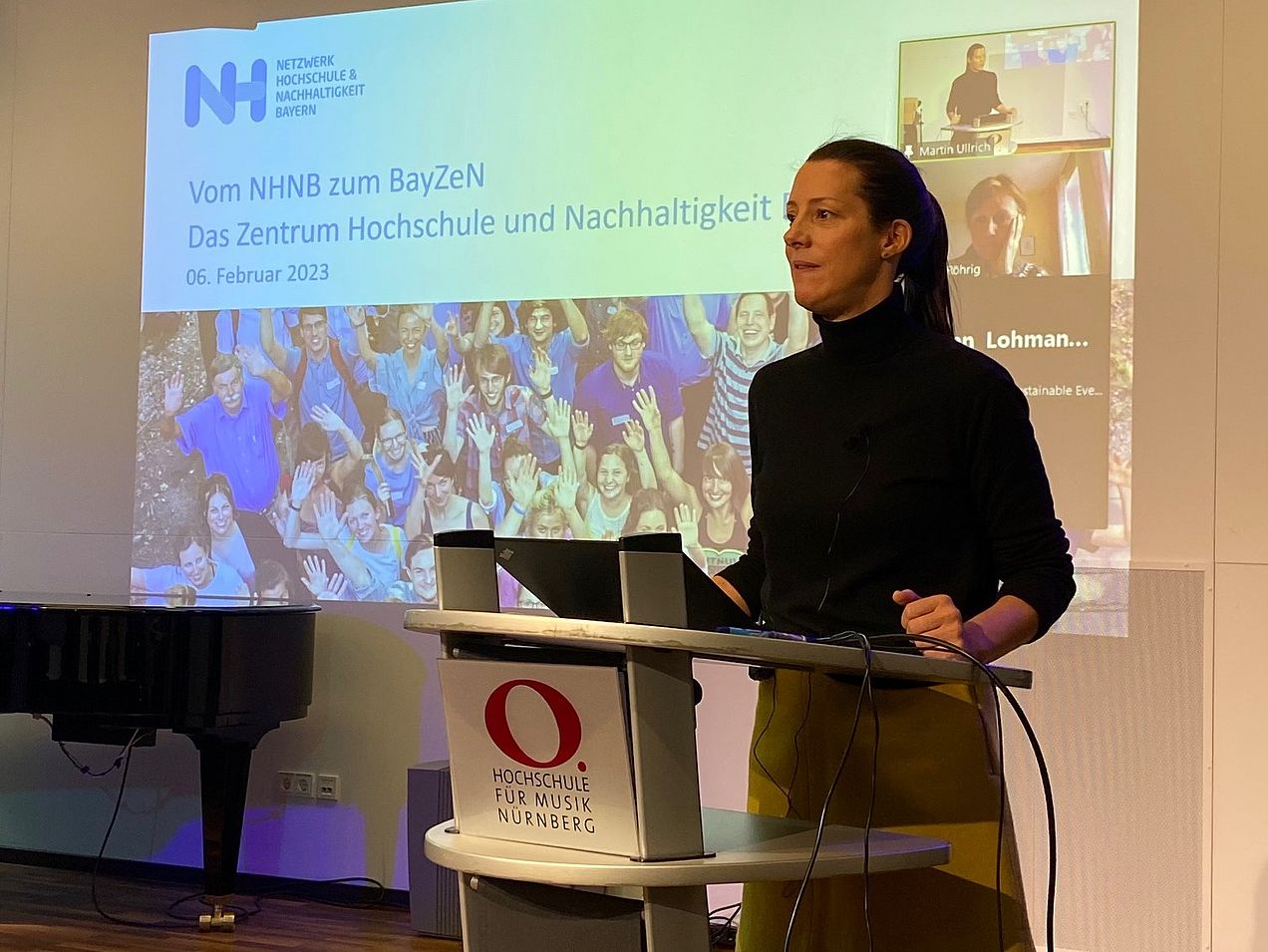 Die Rednerin (Lara Lütke-Spatz) steht am Rednerpult. Hinter ihr ist an der Wand ihre Präsentation über das Zentrum Hochschule und Nachhaltigkeit angeworfen. 
