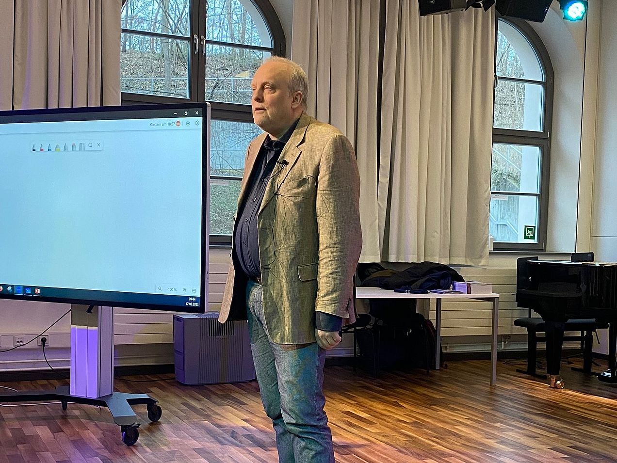 Bernhard König steht mittig im Raum. Rechts neben ihm steht ein Smartboard.