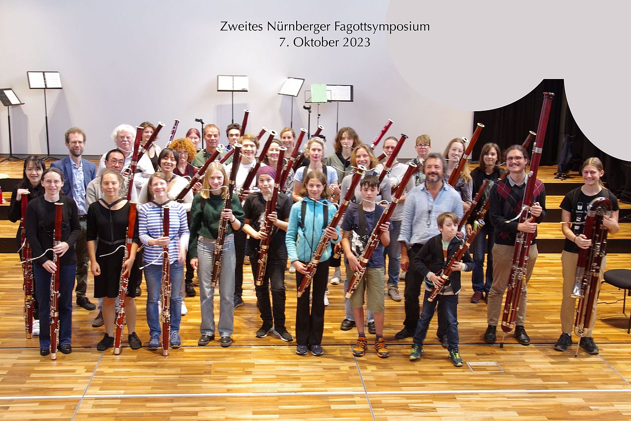 Gruppenbild der Teilnehmer*innen des Fagottsymposiums, die alle ihre Instrumente hochhalten. 