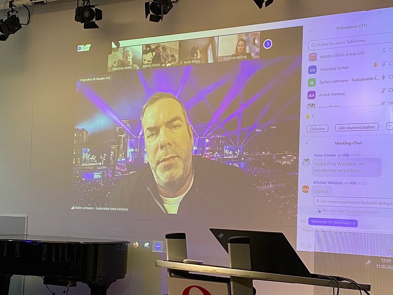 Stefan Lohmann ist zugeschaltet. Sein Bild aus dem Online-Meeting ist an die Wand angestrahlt. 