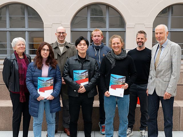 Gruppenbild der Preisträger*innen, Sponsor*innen und Vertretern der Hochscule für Musik Nürnberg. In der ersten Reihe stehen die drei Preisträger*innen und halten ihre Urkunden in den Händen. Dahinter stehen das Ehepaar Schwander, Prof. Rainer Kotzian, Prof. Peter Gahn und Prof. Radoslaw Szarek.  