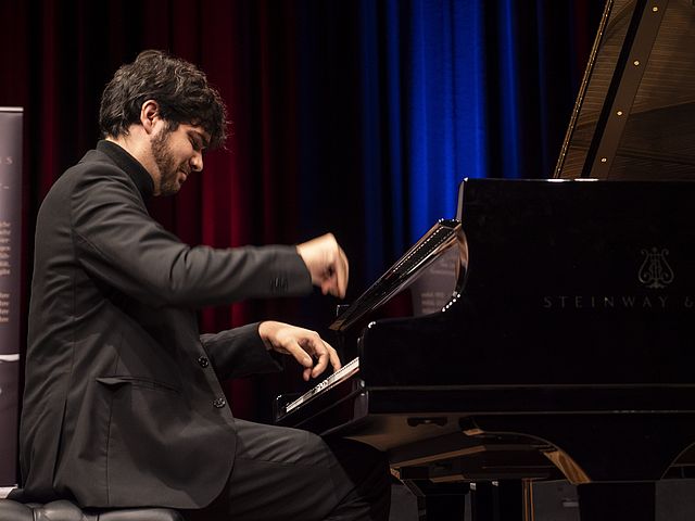 Magi García sitzt am Flügel und spielt. Ansicht von der Seite.