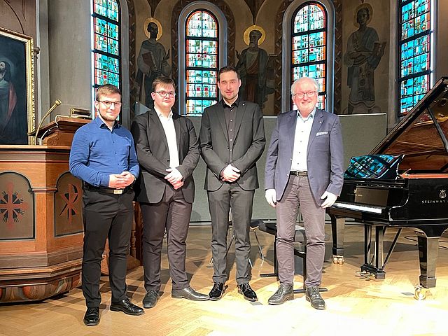 Foto der drei Preisträger und dem Beauftragten des Wettbewerbs, nebeneinander stehend. 