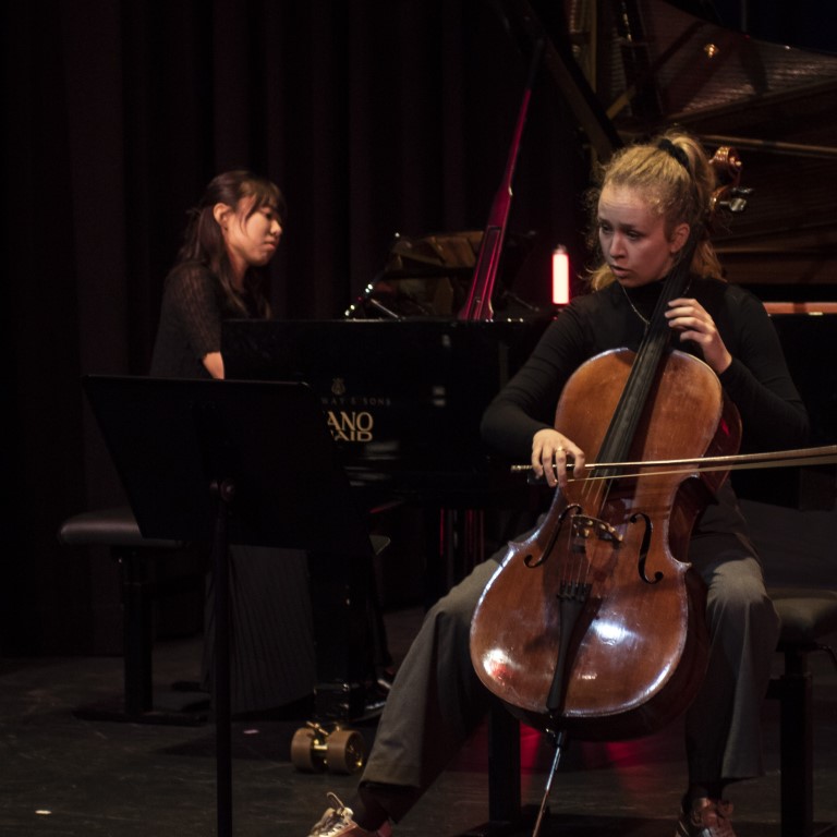 Hannah von Glasow sitzt im Vordergrund und spielt Cello, dahinter befindet sich Chiaya Kakutani am Flügel. 